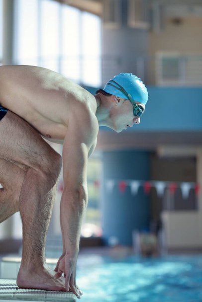 Happy muscular swimmer wearing glasses and cap at swimming pool and represent health and fit concept - 写真・画像