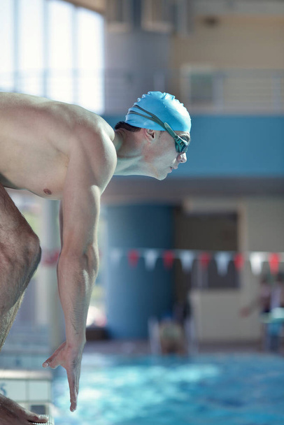 Happy muscular swimmer wearing glasses and cap at swimming pool and represent health and fit concept - Foto, Bild