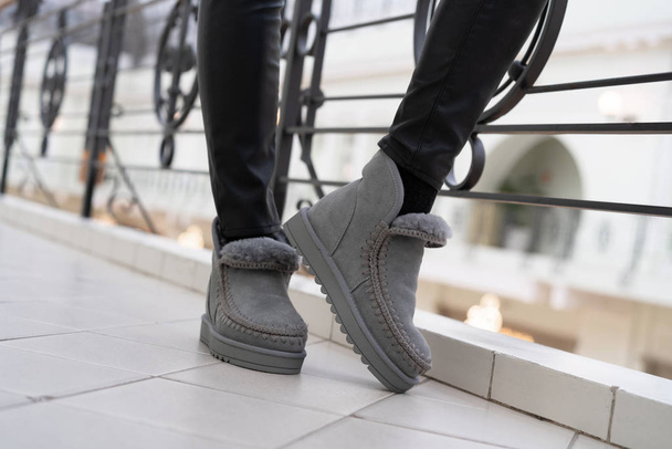 gray female stylish low uggs with fashionable stitching on legs indoors - Foto, Bild