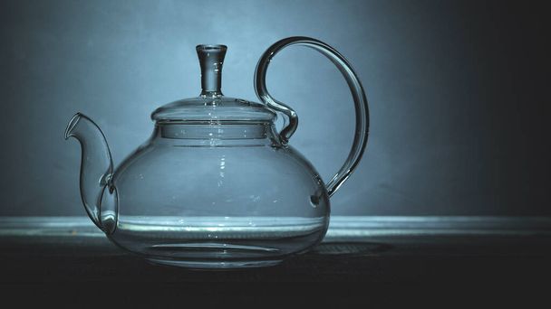 empty glass teapot on black background in spot light, copy space - Zdjęcie, obraz