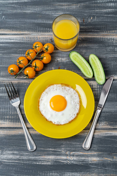 fried egg on yellow plate with cherry tomatoes, cucumber and orange juice. Nutritious breakfast. - Zdjęcie, obraz