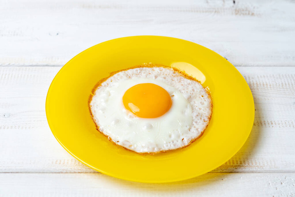 fried egg on yellow plate and white wooden table - Fotoğraf, Görsel