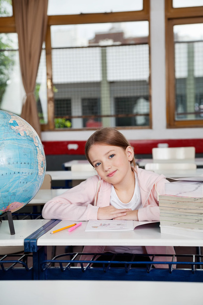 Cute Girl Sitting With Books And Globe At Desk - Photo, image