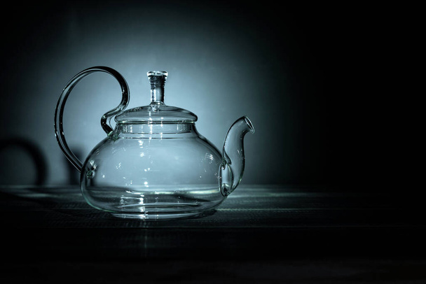 empty glass teapot on black background in spot light, copy space - Foto, Bild