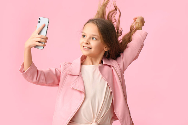 Cute little girl taking selfie on color background - Photo, Image