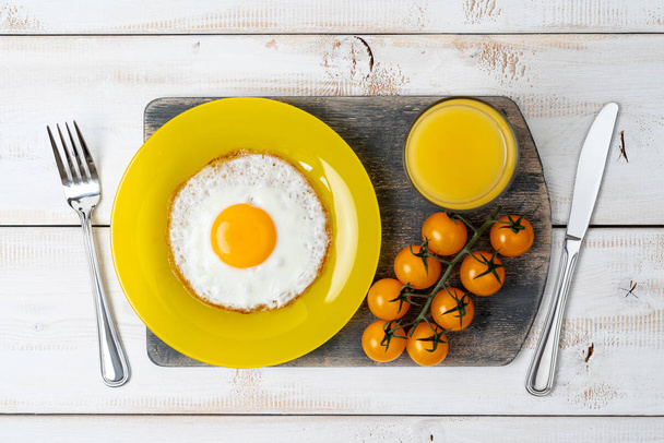 fried egg on yellow plate with orange juice and cherry tomatoes. Tasty breakfast. - Fotoğraf, Görsel