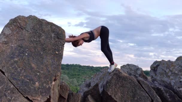 Sportliche Frau, die Yoga und Gymnastikübungen auf Bergklippen mit schöner Landschaft vor Hintergrund praktiziert. Gesunder Lebensstil. Aktives Extrem. - Filmmaterial, Video
