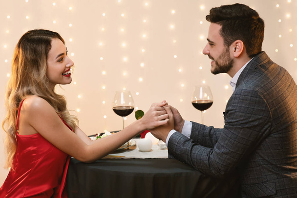 Casal amoroso segurando as mãos no restaurante e olhando um para o outro
 - Foto, Imagem
