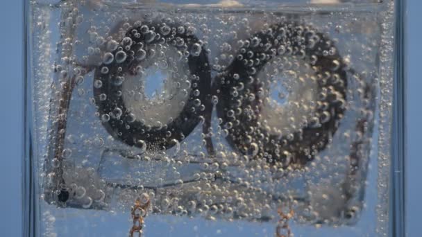 Cassete de áudio flutua na água com bolhas
 - Filmagem, Vídeo