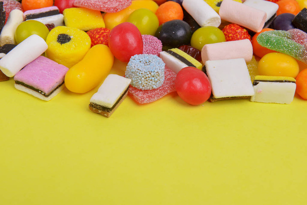 Állítsa be a különböző színes cukorka egy sárga háttér, felső nézet. Vegyes édességek közelsége. A szöveg helye. - Fotó, kép