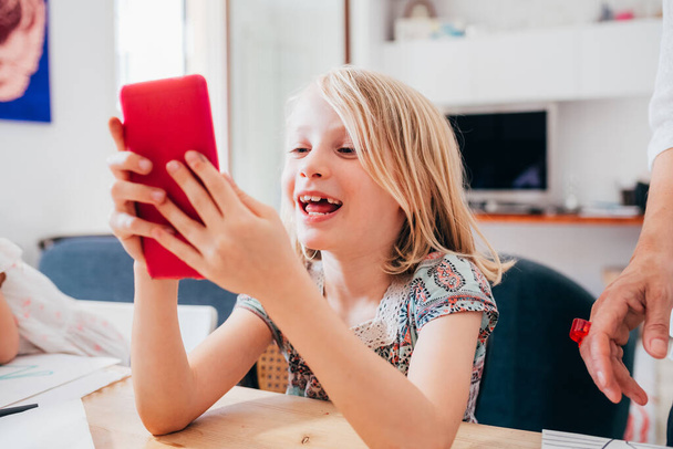 Fiatal digitális natív női gyermek házon belül segítségével smartphon - Fotó, kép