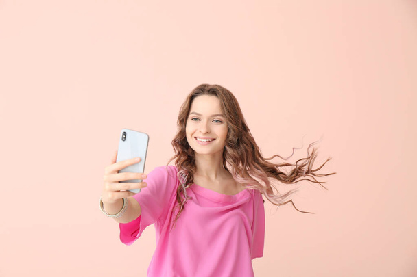Junge Frau macht Selfie auf farbigem Hintergrund - Foto, Bild