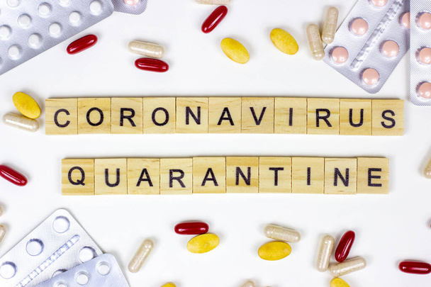 The medical phrase coronavirus quarantine with pills, capsules and tablets on light background. Ncov epidemic alert concept. - Photo, Image