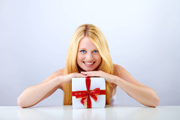 beautiful blonde woman holding a christmas gift is smiling - Foto, afbeelding