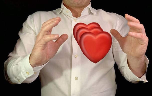 Człowiek ma czerwone serca w rękach. Mężczyzna w białej koszuli ze znakiem serca, na czarnym tle. Koncepcja: dużo miłości - Zdjęcie, obraz