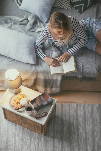 Mujer rubia joven leyendo la historia del libro de papel en casa en la sala de estar. Vista desde arriba. Concepto de Navidad
 - Foto, imagen