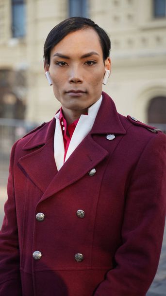 portrait of attractive man in red coat posing outdoor while walking in center of Moscow at sunny day - Фото, зображення