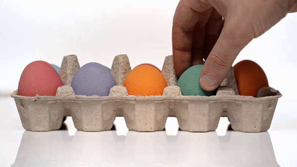 bijgesneden weergave van de mens zetten geschilderde eieren op wit  - Video