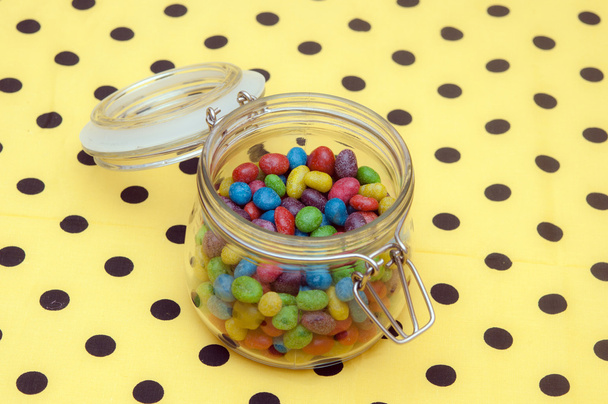 Bonbons colorés dans un pot en verre sur une serviette à pois
 - Photo, image