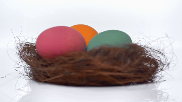 περιστρεφόμενη φωλιά με βαμμένα αυγά σε λευκό  - Πλάνα, βίντεο