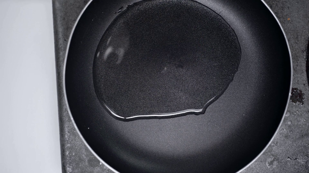 обрізаний вид людини, що поливає олію на сковороду
  - Кадри, відео