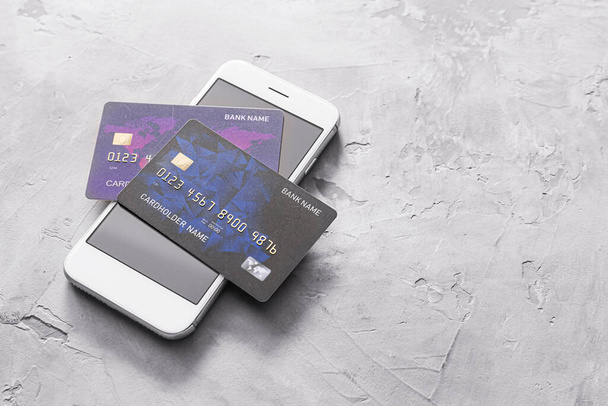 Kredietkaarten met mobiele telefoon op grunge achtergrond. Concept van online bankieren - Foto, afbeelding