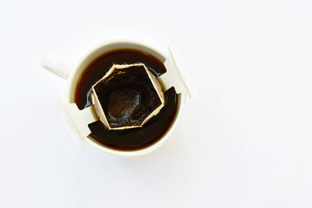  heißes Kaffeetropfenpulver mit Filter in Tasse auf weißem Hintergrund - Foto, Bild