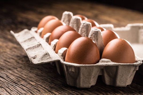 Chicken eggs in carton box on rustic wooden table - Photo, image