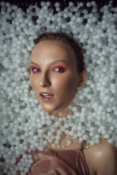 Blonde woman posing in water with balls. - Foto, afbeelding