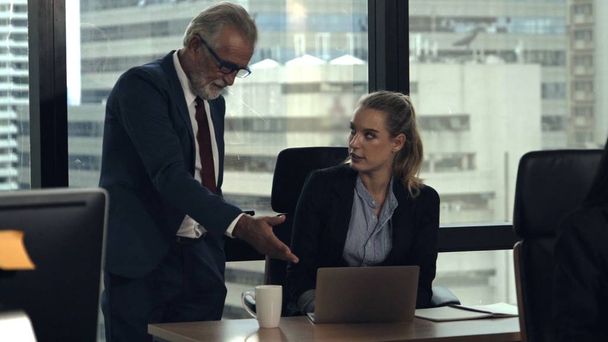 Senior manager gives advice to young woman worker in modern office. Leadership and training concept.;Senior manager gives advice to young woman worker in modern office. Leadership and training concept. - 写真・画像
