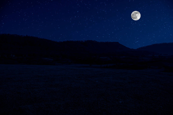 Mountain Road através da floresta em uma noite de lua cheia. Paisagem noturna cênica de estrada rural à noite com grande lua
 - Foto, Imagem