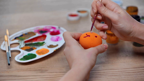 vista cortada da mulher pintando ovo de páscoa laranja  - Filmagem, Vídeo