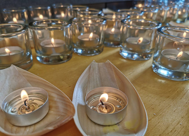 Свечи в маленьких стаканах и лодках во время бдения и молитвы
. - Фото, изображение