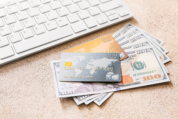 Кредитные карты с деньгами и компьютерной клавиатурой на сером фоне. Концепция онлайн-банкинга
 - Фото, изображение