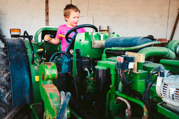 Boy with pink shirt on a farm tractor playing to be a farmer, ge - Foto, Imagem