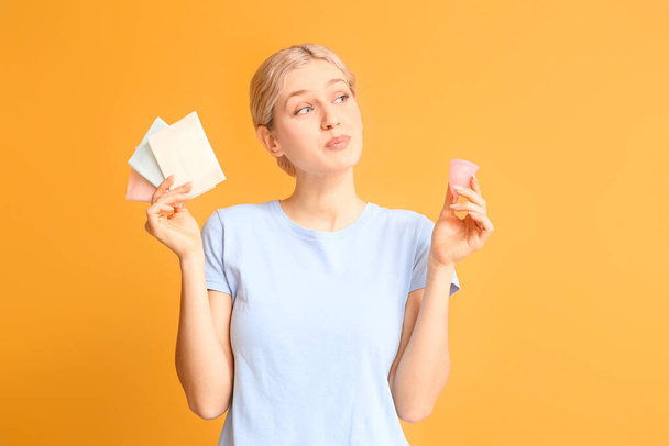 Mladá žena s menstruační pohár a podložky na barevném pozadí - Fotografie, Obrázek