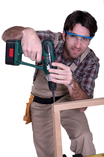 Man drilling into wooden frame - Valokuva, kuva