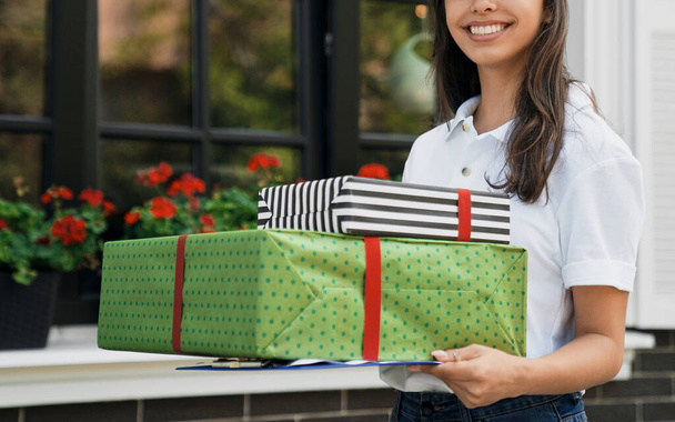 Female courier holding gift boxes and folder. - Photo, Image