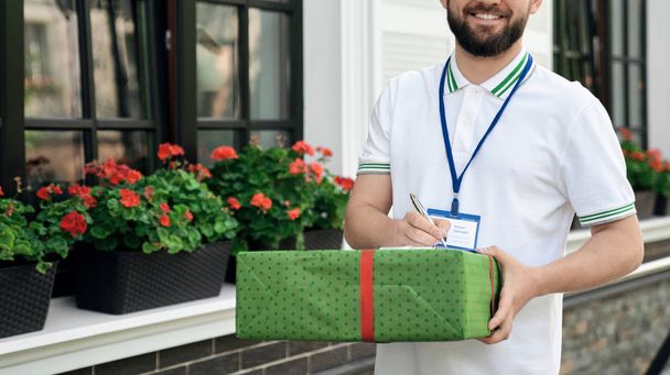 Deliveryman holding gift box and folder. - Photo, Image