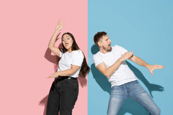 Young emotional man and woman on pink and blue background - Foto, imagen
