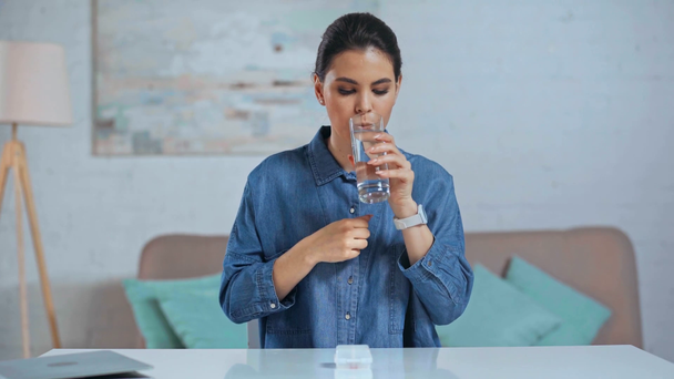 sick woman taking pill and drinking water - Кадри, відео