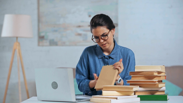 mulher chateada trabalhando perto de laptop e livros
  - Filmagem, Vídeo