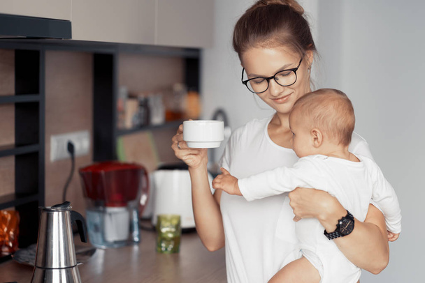 Young mother with baby in the kitchen - Fotoğraf, Görsel