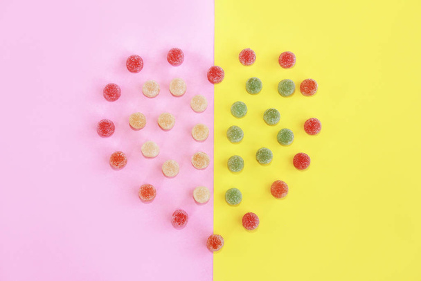 serce wykonane ze słodkich wielokolorowych okrągłych cukierków marmoladowych z posypką cukru na żółtym różowym tle - Zdjęcie, obraz