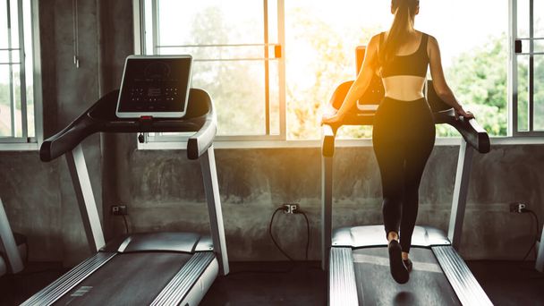 Female muscular feet in sneakers running on the treadmill at the gym. Concept for fitness, exercising and healthy lifestyle.sport concept. Young sporty woman stretching at gym. Change for health concept.Fitness woman in training showing exercises wit - 写真・画像