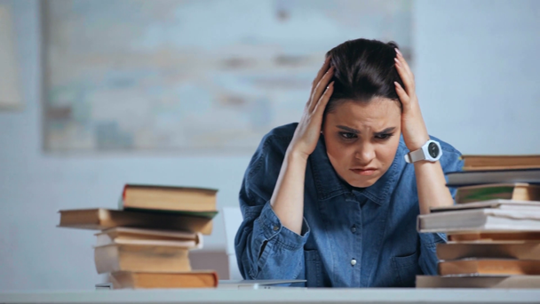 αναστατωμένη γυναίκα κοιτάζοντας τα βιβλία στο γραφείο - Πλάνα, βίντεο