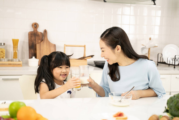 Healthy food at home and Happy family in the kitchen concept. Mother and child daughter are having breakfast.Cute little girl and her beautiful parents are making breakfast while cooking in kitchen. - Fotoğraf, Görsel