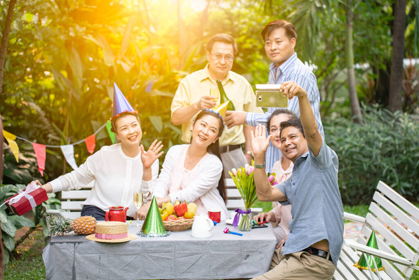 Idős párok mosolygott a kertben.Idős ázsiai emberek csoportja, akik együtt élvezik a BBQ pálcikákat az alkohollal.Idősek csoportja otthon szelfit készít. - Fotó, kép