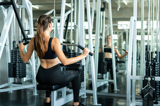 Fitness woman in training showing exercises with exercise-machine in gym, fitness concept, sport concept. Young sporty woman stretching at gym. Change for health concept. - 写真・画像