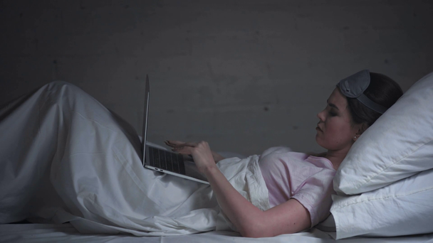Yatakta dizüstü bilgisayar kullanan yorgun kadının yan görüntüsü - Video, Çekim